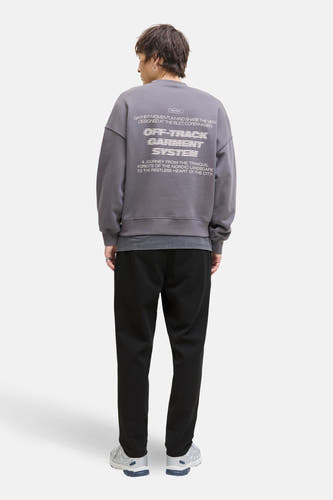 Pantalon noir de JACK & JONES JEANS INTELLIGENCE, combiné avec un pull gris à imprimé au dos et des baskets.