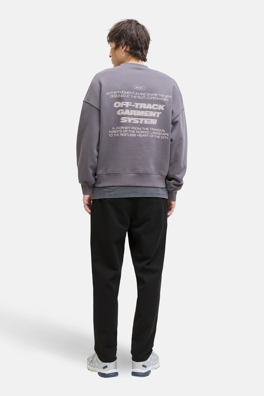 Pantalon noir de JACK & JONES JEANS INTELLIGENCE, combiné avec un pull gris à imprimé au dos et des baskets.