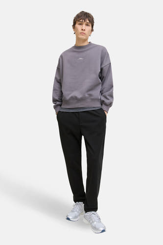 Pantalon noir de JACK & JONES JEANS INTELLIGENCE, stylé avec un pull gris et des baskets blanches.