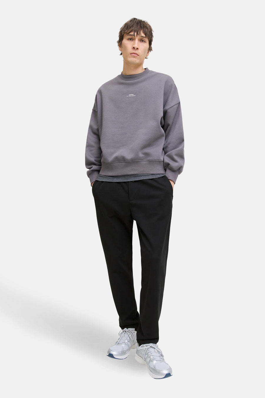 Pantalon noir de JACK & JONES JEANS INTELLIGENCE, stylé avec un pull gris et des baskets blanches.