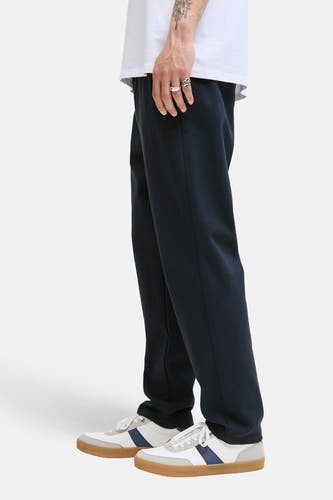 Pantalon bleu de JACK & JONES JEANS INTELLIGENCE, avec des chaussures blanches et des bagues argentées.