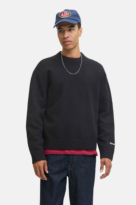 Pull noir à col rond de ORIGINALS BY JACK & JONES, avec manches longues et un t-shirt rouge en dessous.