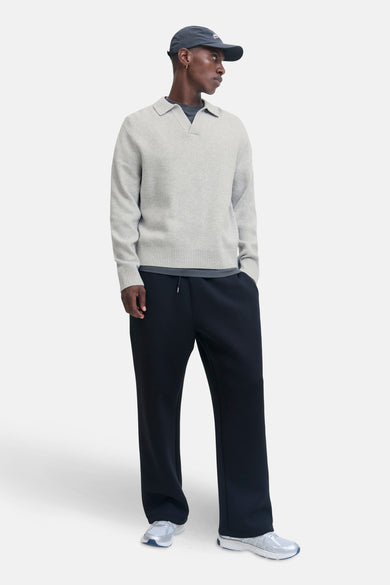 Sweat-shirt gris à col V de CORE BY JACK & JONES, porté sur un t-shirt gris foncé, avec un pantalon de jogging noir et des baskets argentées.