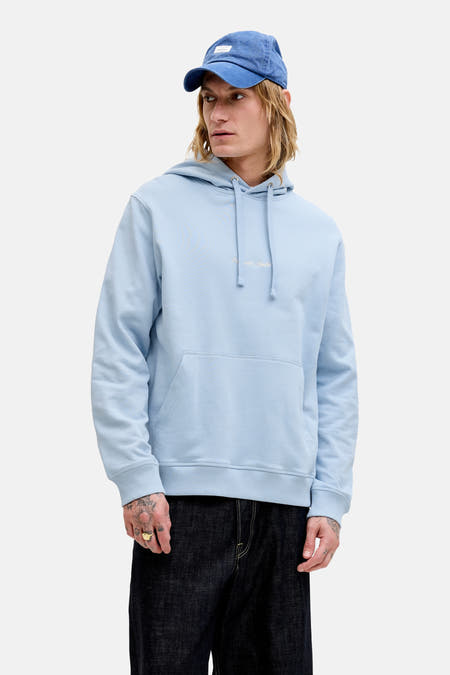 Sweat à capuche bleu de ORIGINALS by JACK & JONES, porté par un homme avec une casquette bleue, une veste en daim marron et un jean foncé.