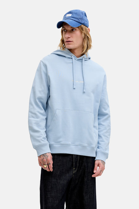 Sweat à capuche bleu de ORIGINALS by JACK & JONES, porté par un homme avec une casquette bleue, une veste en daim marron et un jean foncé.