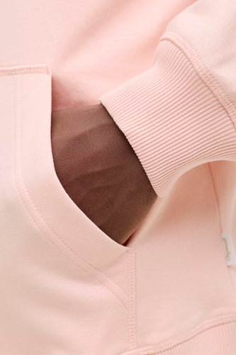 Roze hoodie met ribgebreide manchetten, hand in zak.
