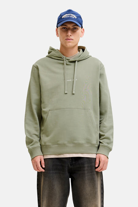 Sweat à capuche vert de ORIGINALS BY JACK & JONES, porté sous une chemise en jean bleue et un jean noir ample.