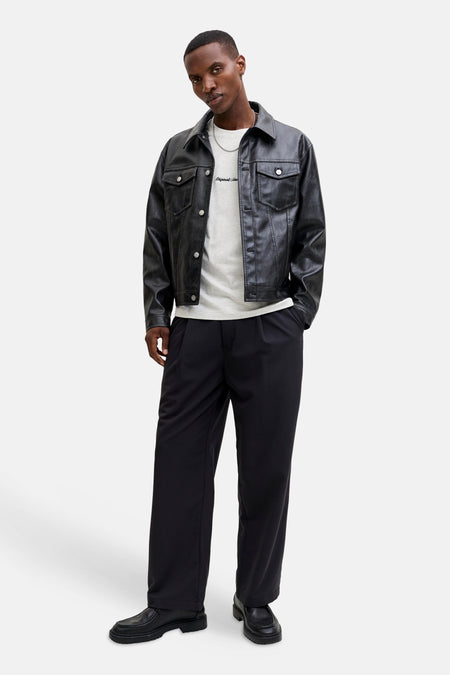 Man in zwarte leren jas, grijze shirt en zwarte broek.