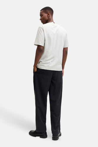 Achterkant van een man met een grijs T-shirt, zwarte broek en schoenen.