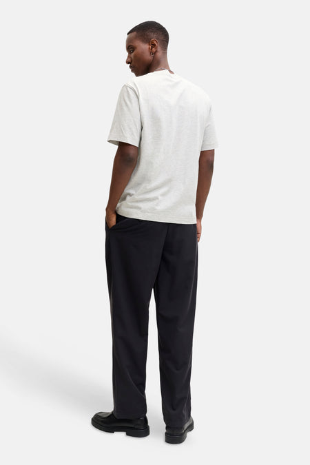 Achterkant van een man met een grijs T-shirt, zwarte broek en schoenen.