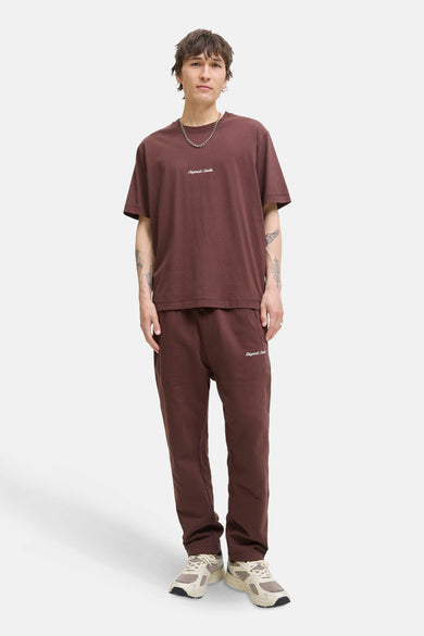 T-shirt brun à manches courtes d'ORIGINALS BY JACK & JONES, porté avec un pantalon de jogging coordonné et une chaîne en argent.