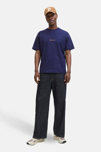 T-shirt bleu à manches courtes d'ORIGINALS BY JACK & JONES, porté avec des jeans foncés et des baskets beige.