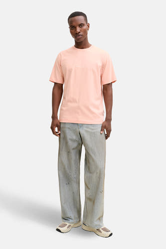 T-shirt rose à manches courtes de ORIGINALS BY JACK & JONES, porté avec un jean ample et des baskets couleur crème.