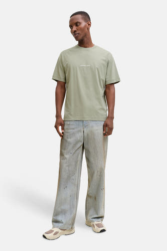 T-shirt vert à manches courtes ORIGINALS BY JACK & JONES, porté avec un jean décontracté et des baskets de couleur crème.