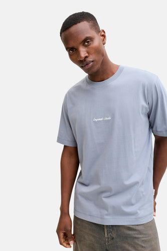 Een man in een blauw shirt met een opdruk, gedeeltelijk zichtbaar.