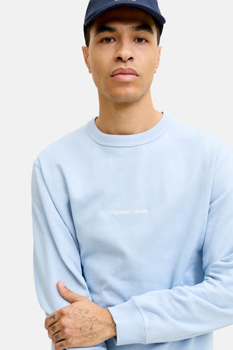 Pull bleu clair à col rond de ORIGINALS BY JACK & JONES, avec inscription brodée blanche 'Originals Studio' sur la poitrine.