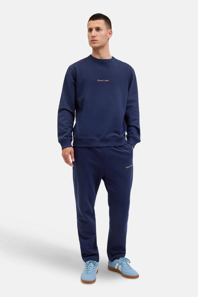 Pull-over bleu d'ORIGINALS BY JACK & JONES, avec des manches longues et le nom de la marque sur la poitrine, porté avec un short de jogging coordonné et des baskets bleu clair.