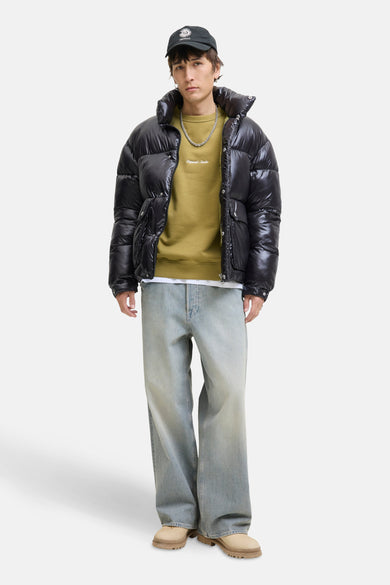 Sweater vert de ORIGINALS BY JACK & JONES, avec une impression blanche et associé à un manteau polaire noir et des jeans larges.