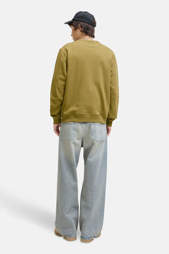 Pull-over vert de un col rond originalSSS & & J, porté avec des large et jeans panton.