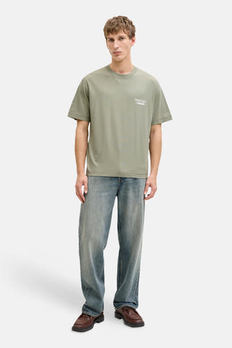 Groen T-shirt met korte mouwen van ORIGINALS BY JACK & JONES, met witte tekstprint, gecombineerd met jeans en bruine schoenen.