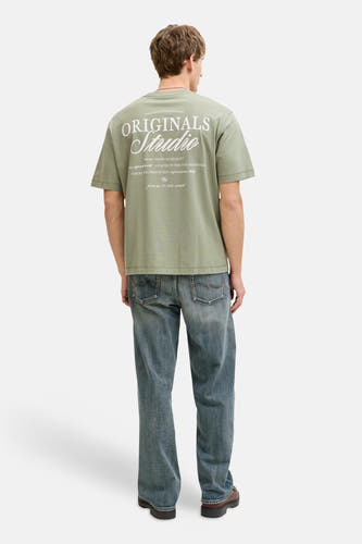 T-shirt vert à manches courtes ORIGINALS BY JACK & JONES, avec imprimé texte au dos, porté avec un jean bleu et des chaussures marron.