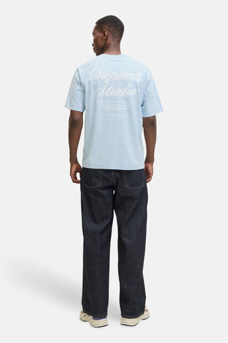 T-shirt bleu à manches courtes de ORIGINALS BY JACK & JONES, avec imprimé texte blanc au dos, porté avec un jean foncé.