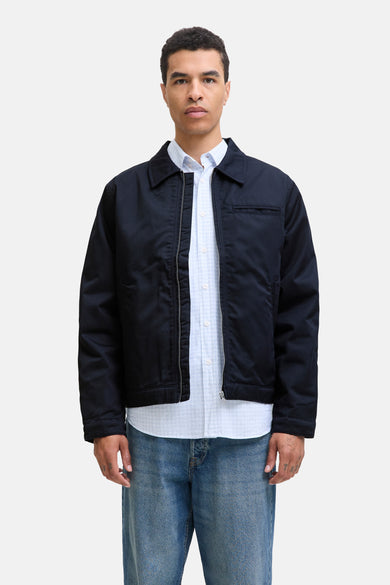 Manteau court bleu d'ORIGINALS BY JACK & JONES porté sur une chemise bleue claire à carreaux et un jean.