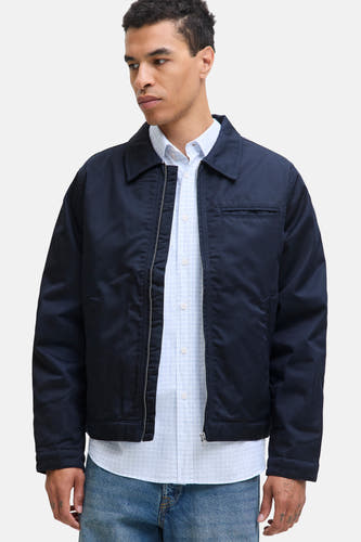 Manteau court bleu d'ORIGINALS BY JACK & JONES, avec fermeture éclair et chemise bleue claire en dessous, associé à des jeans.