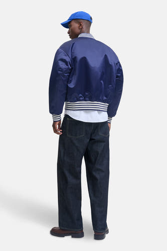 Veste bleue d'ORIGINALS BY JACK & JONES, avec des bordures rayées, portée avec un chemisier rayé et un jeans foncé.