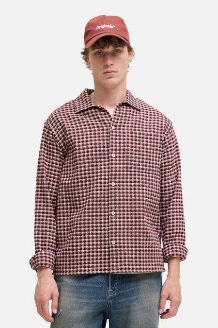 Rouge, t-shirt à manches longues d'ORIGINALS BY JACK & JONES, avec un motif à carreaux et une coupe décontractée, porté avec un chapeau.