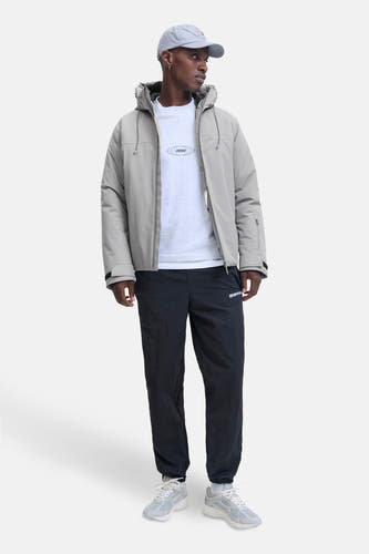 Manteau court gris de CORE BY JACK & JONES, avec capuche et pantalon de jogging noir et baskets grises.