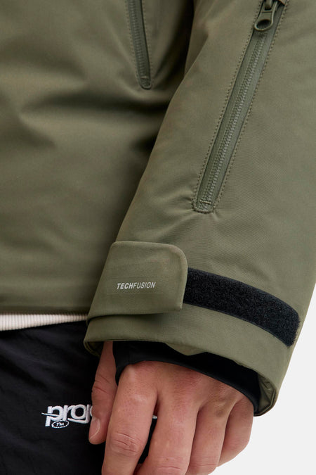Veste courte verte de CORE BY JACK & JONES avec détail de manche : fermeture éclair verticale, texte 'TECHFUSION' et fermeture auto-agrippante.
