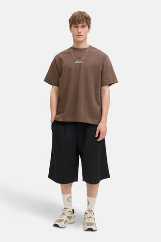 T-shirt marron à manches courtes de CORE BY JACK & JONES, avec une chaîne argentée, des short noirs et des baskets beige.