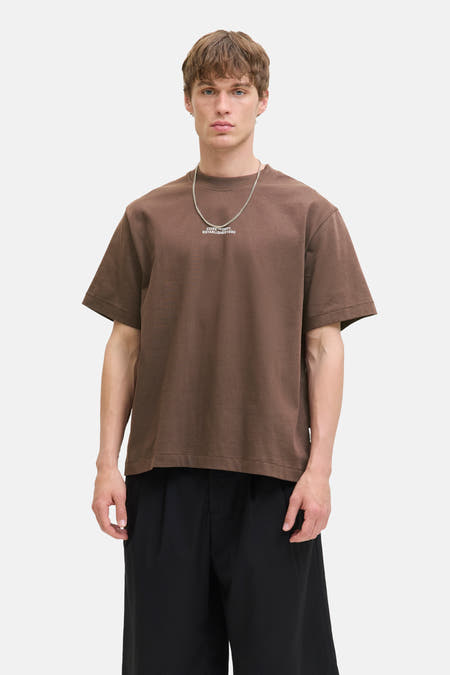 T-shirt brun à manches courtes de CORE BY JACK & JONES, avec une chaîne argentée et un pantalon noir.