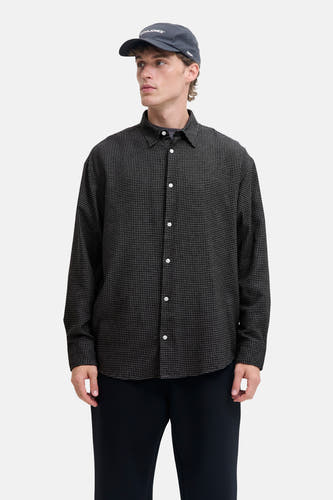 T-shirt à manches longues noir de CORE BY JACK & JONES, avec un motif à carreaux, des boutons blancs et une casquette sombre.
