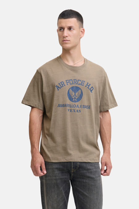 T-shirt Kaki à manches courtes de PREMIUM BLUE par JACK & JONES, avec une impression bleue et porté avec des jeans gris.