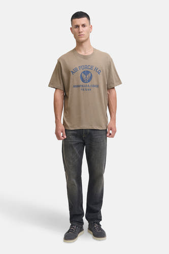 T-shirt Kaki à manches courtes de PREMIUM BLUE par JACK & JONES, avec du texte et un logo bleus, associé à des jeans foncés et des chaussures.