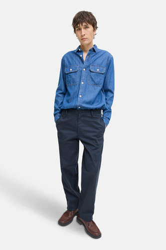 Blauwe chino van JACK & JONES JEANS INTELLIGENCE, gedragen met een denim overhemd en bruine schoenen.