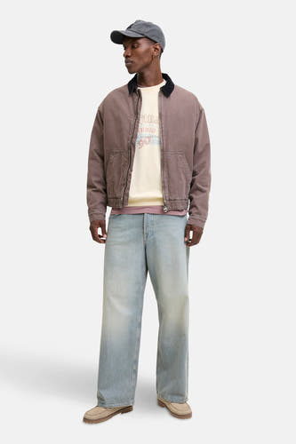 Pull beige d'ORIGINALS BY JACK & JONES, porté avec un manteau brun, des jeans larges et un chapeau gris.