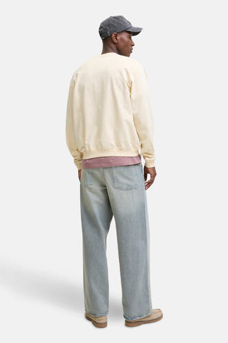 Gilet beige d'ORIGINALS BY JACK & JONES, avec des manches longues et un col rond, porté avec un chapeau et des jeans larges.