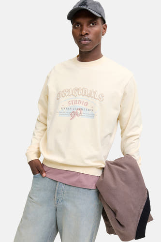 Gilet beige d'ORIGINALS BY JACK & JONES, avec un imprimé vintage sur l'avant, porté avec un chapeau et des jeans.