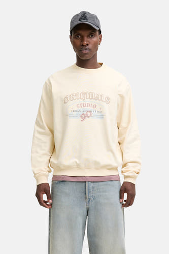Gilet beige d'ORIGINALS BY JACK & JONES, avec un imprimé vintage sur la poitrine, associé à des jeans bleus et une casquette grise.