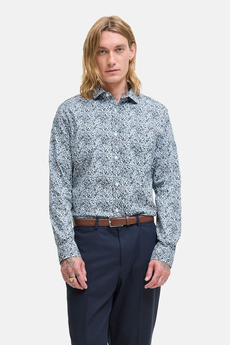 Chemise bleue à manches longues de PREMIUM by JACK & JONES, imprimée de fleurs, associée à une ceinture marron et un pantalon bleu marine.