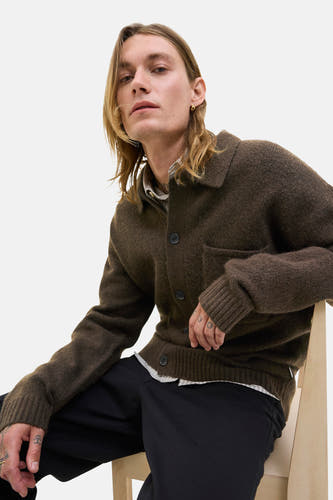 Gilet brun de PREMIUM BLUE par JACK & JONES, avec fermeture à boutons et une poche po poitrine, porté sur un chemisier rayé et un pantalon noir.