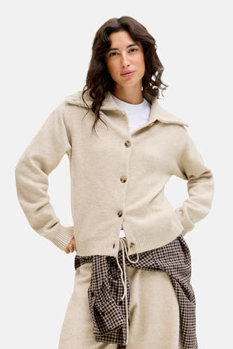 Gilet beige de JJXX, avec des manches longues et un col classique, associé à une chemise à carreaux.