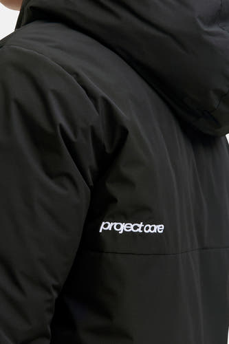 Veste courte noire de CORE BY JACK & JONES avec une subtile texture ripstop, une capuche et une broderie blanche "project core".