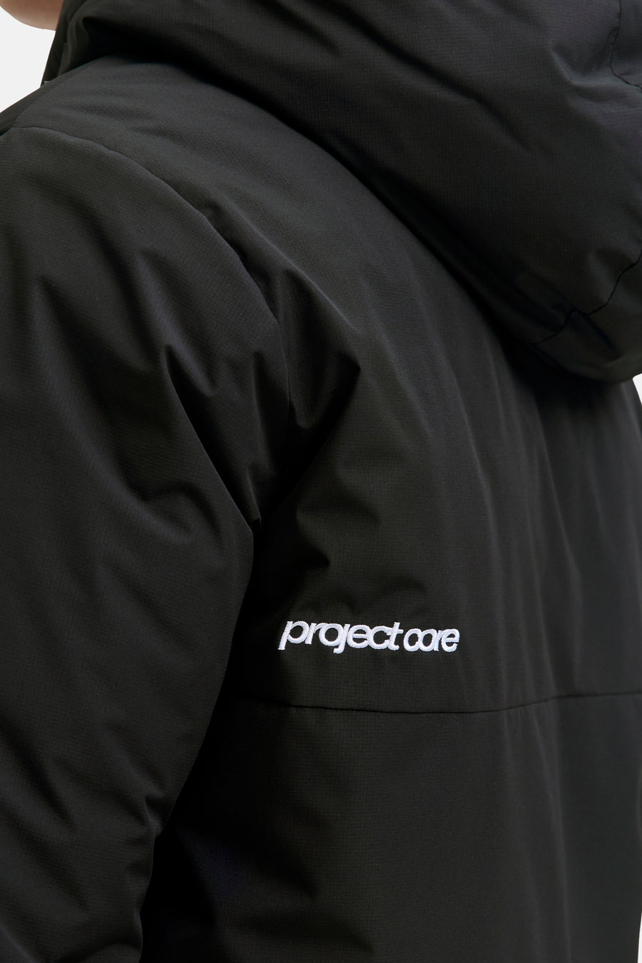 Veste courte noire de CORE BY JACK & JONES avec une subtile texture ripstop, une capuche et une broderie blanche "project core".