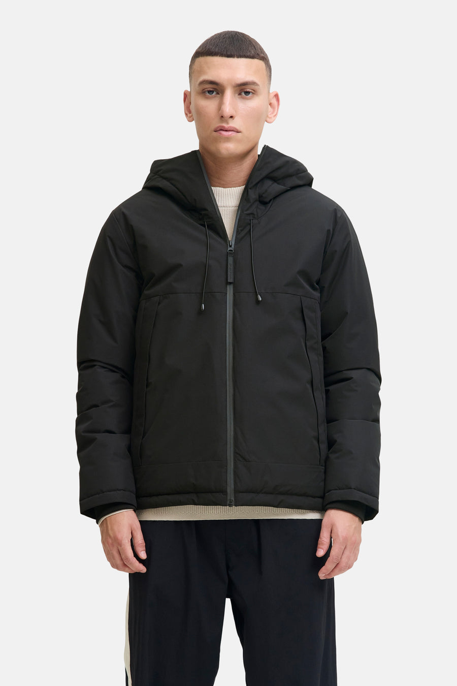 Veste courte noire de CORE BY JACK & JONES avec capuche et logo blanc sur la manche, portée par un homme de profil.