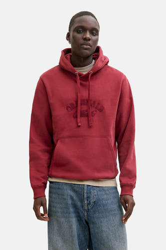 Pull-over rouge avec capuche d'ORIGINALS BY JACK & JONES, porté sous une veste beige et des jeans larges.