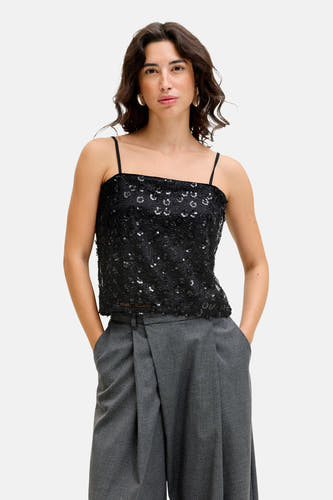 Blouse sans manches noire de JJXX, finie avec des paillettes, associée à un pantalon gris.